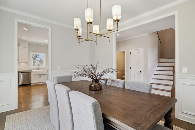 dining area with dark wood-style floors, a wainscoted wall, crown molding, stairway, and a chandelier