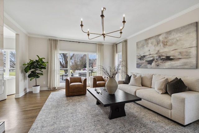 living room with a chandelier, crown molding, baseboards, and wood finished floors