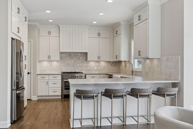 kitchen featuring stainless steel appliances, white cabinetry, a sink, and a peninsula