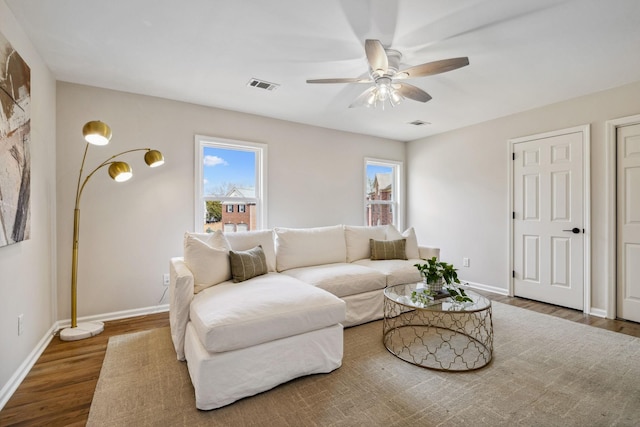 living room with a ceiling fan, baseboards, visible vents, and wood finished floors