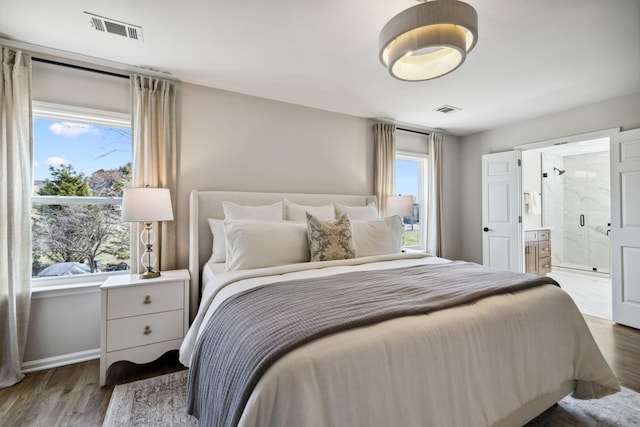 bedroom with connected bathroom, visible vents, and wood finished floors