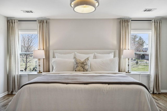 bedroom with baseboards, visible vents, and wood finished floors