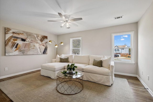 living room featuring a ceiling fan, baseboards, visible vents, and wood finished floors