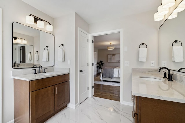 bathroom with marble finish floor, connected bathroom, two vanities, and a sink