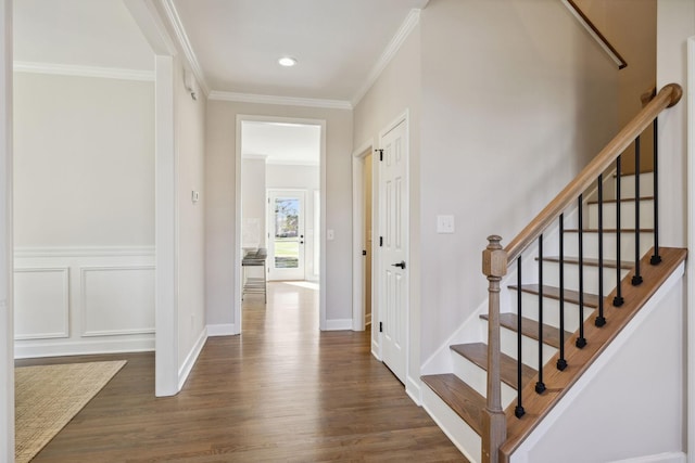 interior space with crown molding, a decorative wall, baseboards, and wood finished floors