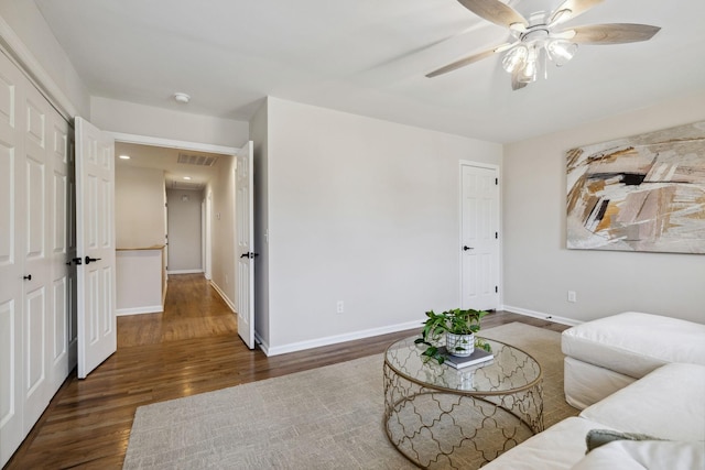 living area with a ceiling fan, wood finished floors, visible vents, and baseboards