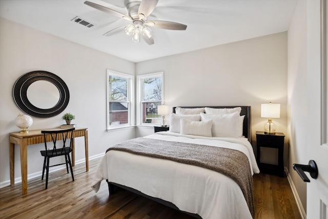 bedroom featuring ceiling fan, wood finished floors, visible vents, and baseboards