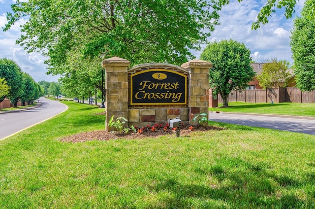 community / neighborhood sign with a yard and fence