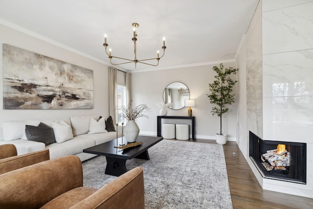 living area with baseboards, dark wood finished floors, crown molding, a fireplace, and a notable chandelier