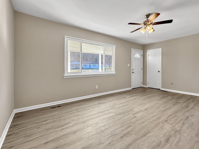 spare room featuring a ceiling fan, visible vents, baseboards, and wood finished floors