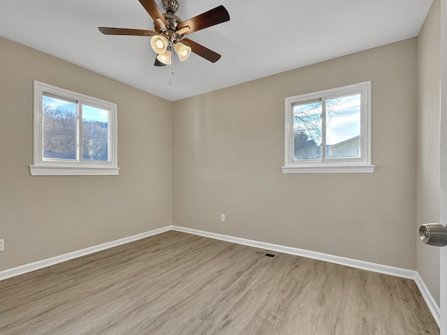 empty room featuring light wood-style floors, visible vents, plenty of natural light, and baseboards