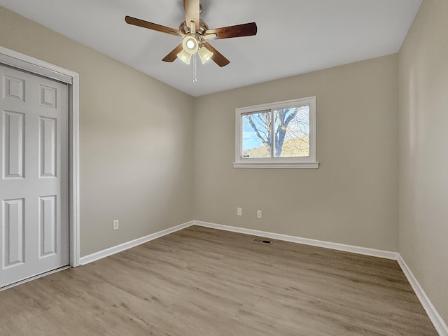 unfurnished bedroom featuring a ceiling fan, visible vents, baseboards, and wood finished floors