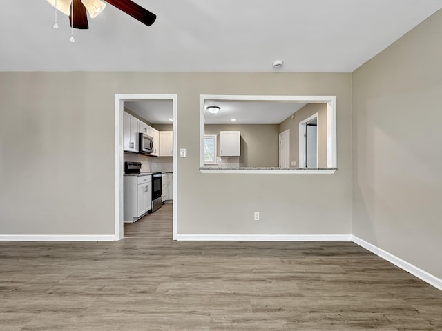 spare room with a ceiling fan, baseboards, and wood finished floors