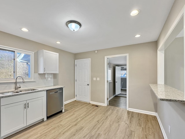 kitchen with baseboards, decorative backsplash, light wood-style flooring, stainless steel dishwasher, and a sink