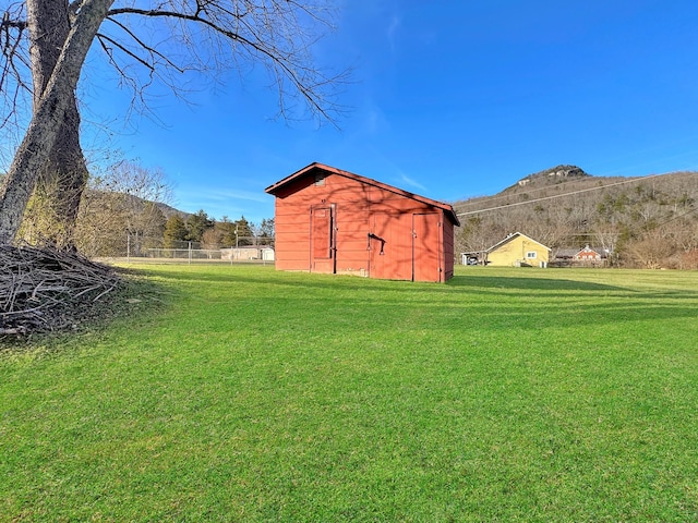 view of yard with a shed, fence, a mountain view, and an outdoor structure