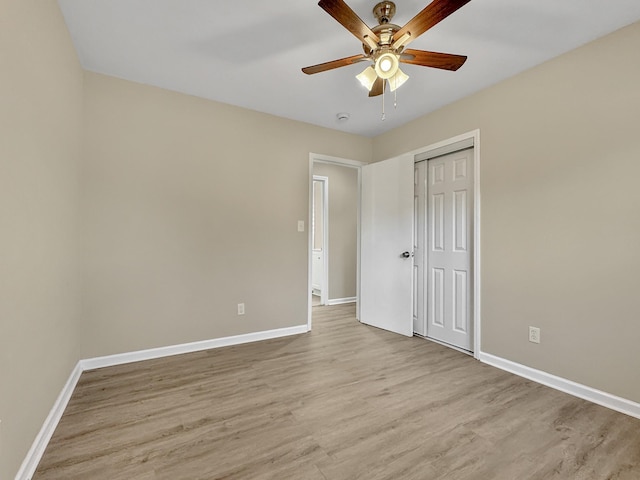 unfurnished bedroom featuring light wood-style flooring, baseboards, and a closet