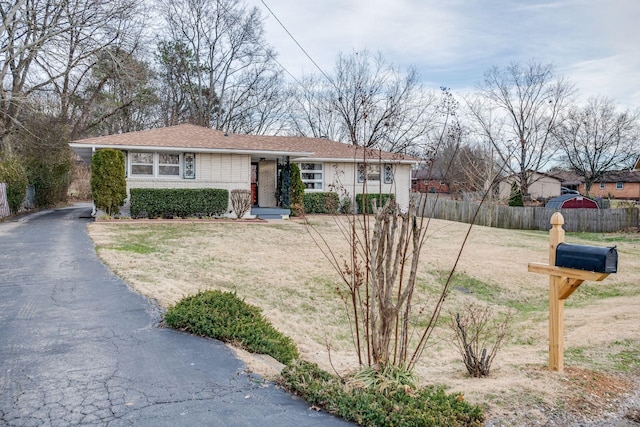 ranch-style house featuring a front yard, fence, and brick siding