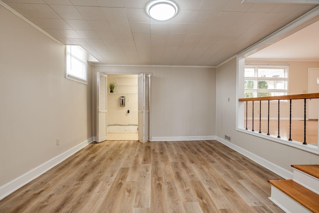 unfurnished room featuring light wood-type flooring, baseboards, and ornamental molding