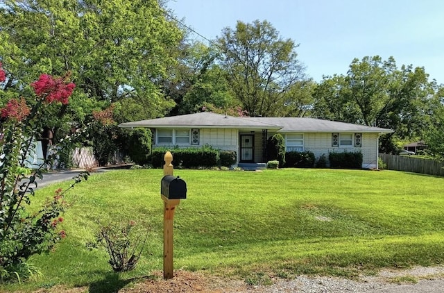 ranch-style home featuring fence, a front lawn, and brick siding