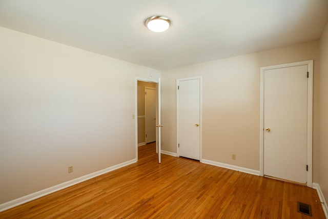 unfurnished bedroom featuring baseboards, visible vents, and light wood finished floors