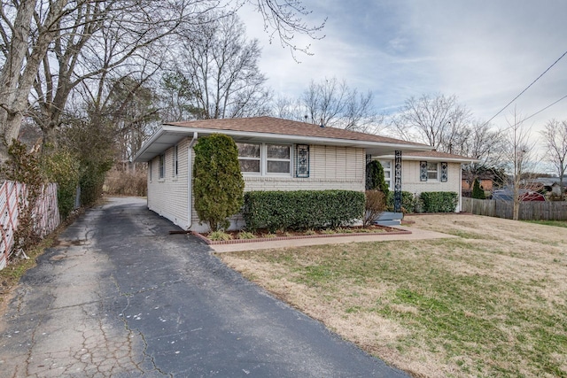 view of front of house featuring aphalt driveway, a front yard, fence, and brick siding