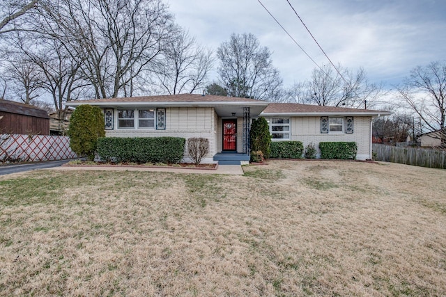 ranch-style home featuring fence, a front lawn, and brick siding