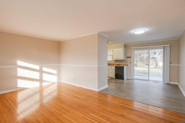 unfurnished living room with crown molding, light wood-style flooring, and baseboards