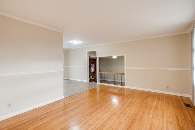 spare room featuring ornamental molding, visible vents, and wood finished floors