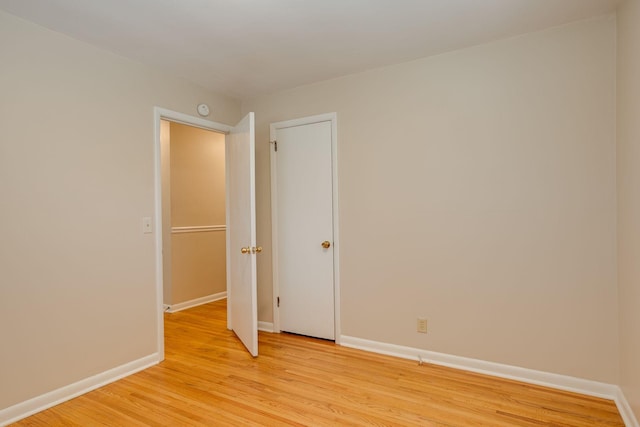 spare room with baseboards and light wood-style floors