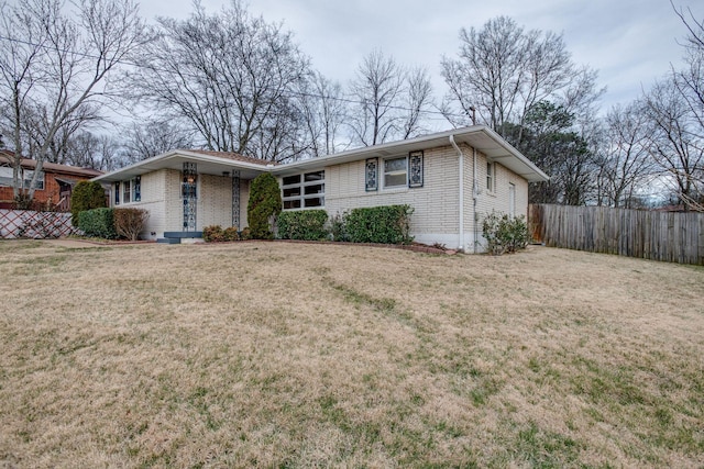 view of front of home with brick siding, a front yard, and fence