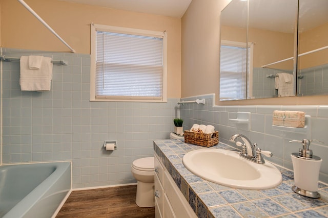 full bath featuring toilet, wood finished floors, vanity, washtub / shower combination, and tile walls