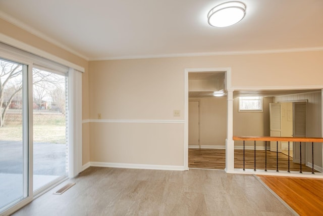 empty room with visible vents, baseboards, wood finished floors, crown molding, and ornate columns