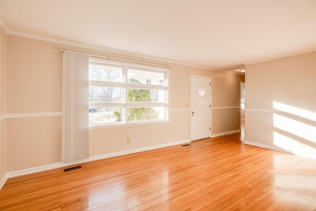 spare room with light wood-style floors, baseboards, visible vents, and ornamental molding