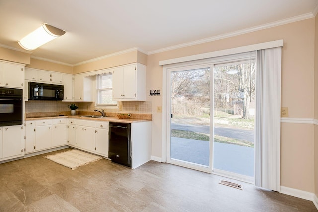 kitchen with crown molding, visible vents, decorative backsplash, a sink, and black appliances