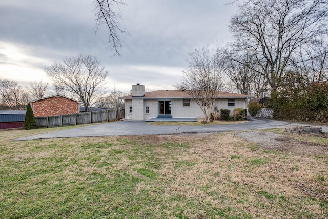 back of property featuring a patio, fence, driveway, a lawn, and a chimney