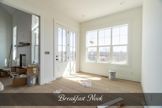 doorway to outside featuring baseboards, a fireplace, visible vents, and wood finished floors