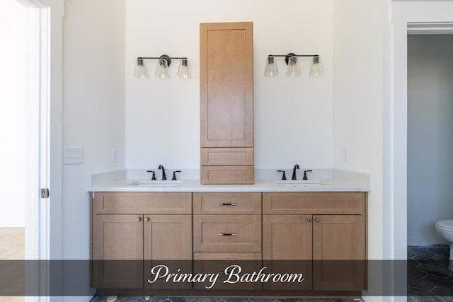 bathroom featuring double vanity, a sink, and toilet