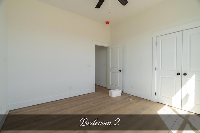 unfurnished bedroom with a closet, ceiling fan, baseboards, and wood finished floors