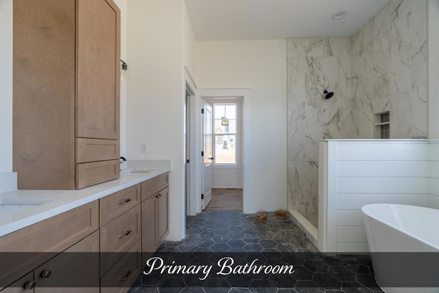 full bathroom featuring tile walls, a marble finish shower, double vanity, a freestanding bath, and a sink