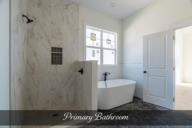 bathroom featuring a soaking tub, wainscoting, tile walls, and a marble finish shower