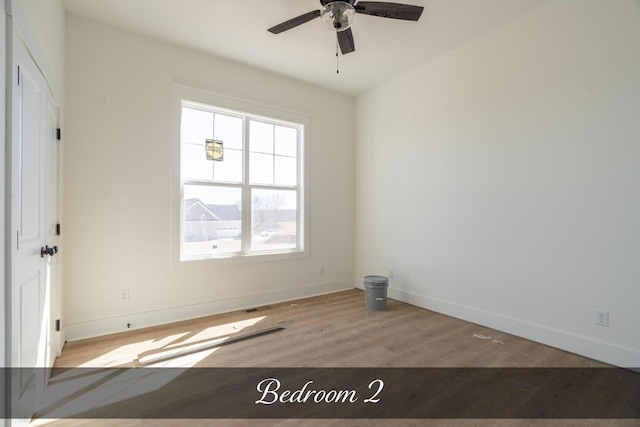 empty room with a ceiling fan, baseboards, and wood finished floors