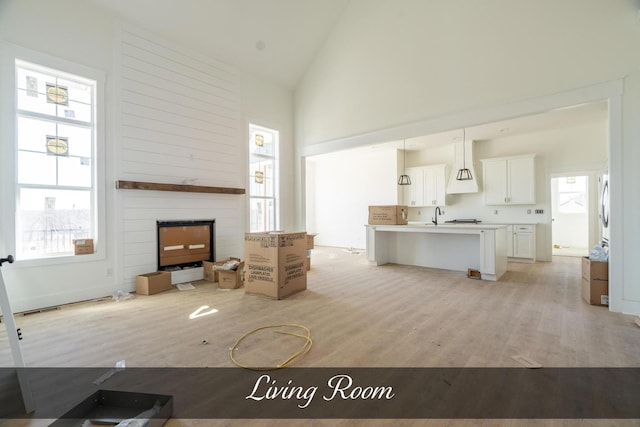 living room featuring high vaulted ceiling, a fireplace, visible vents, and light wood-style floors