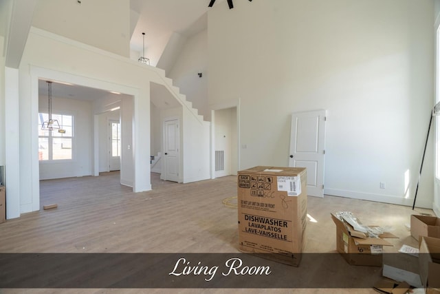 living area with high vaulted ceiling, stairs, baseboards, and wood finished floors