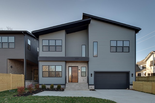 view of front of house with a garage, concrete driveway, and fence