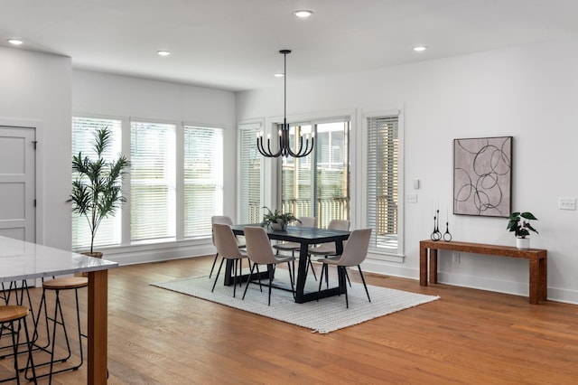 dining space with baseboards, recessed lighting, light wood-style flooring, and a notable chandelier