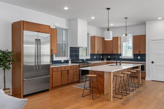 kitchen featuring brown cabinetry, light wood-style flooring, and high quality appliances