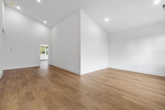 spare room with recessed lighting, visible vents, wood finished floors, high vaulted ceiling, and baseboards