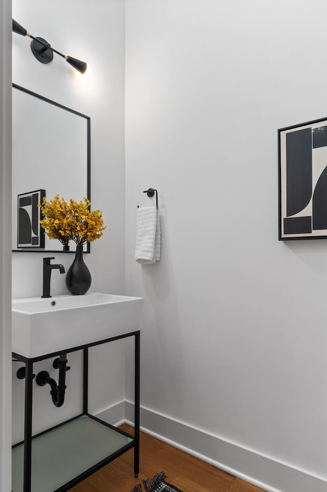 bathroom with a sink, baseboards, and wood finished floors