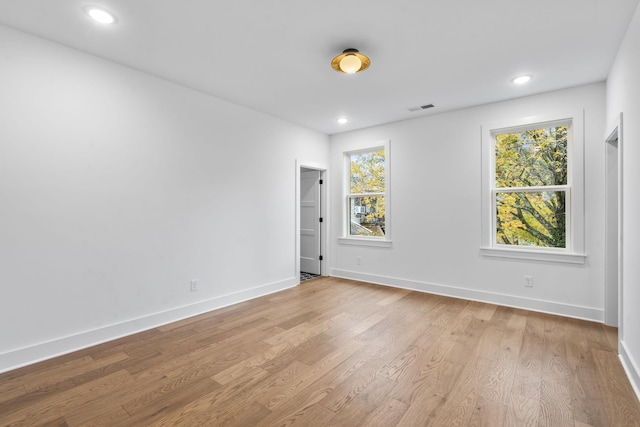 spare room with baseboards, a healthy amount of sunlight, and light wood finished floors