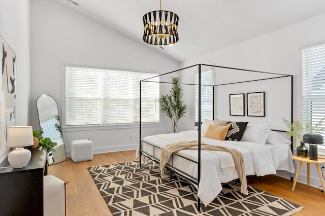 bedroom with vaulted ceiling, multiple windows, and wood finished floors